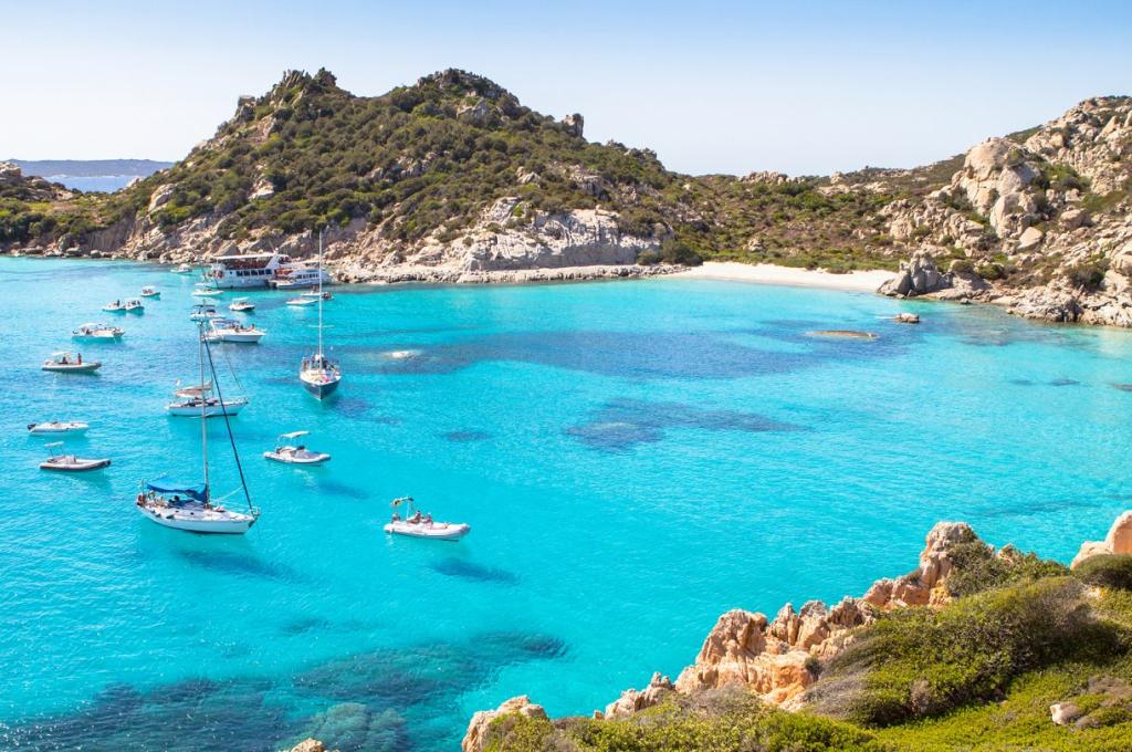 baia con barche a vela e gommoni